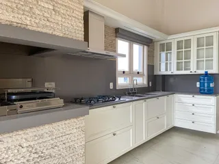 Cozinha moderna com armários brancos e bancadas escuras.
