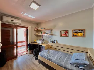 Quarto com piso de madeira e porta de vidro abrindo para o exterior.