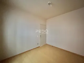 Ambiente interno de uma sala com piso de madeira clara e paredes brancas.