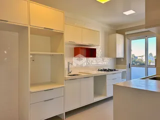 Vista da cozinha moderna com armários brancos e bancadas claras.