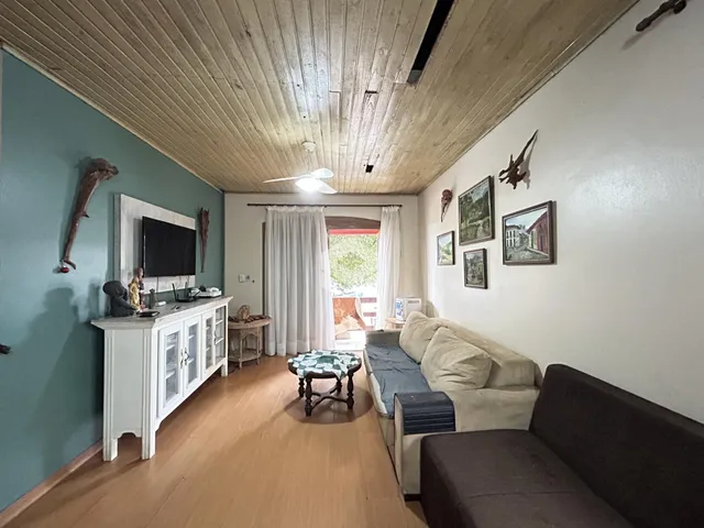 Interior de uma sala de estar com piso de madeira e teto de madeira.