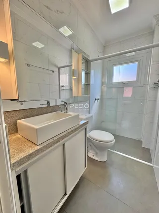 Banheiro com revestimento de mármore branco e piso claro.