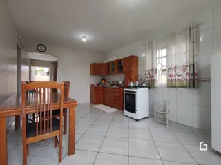 Foto de uma sala de jantar com mesa de madeira e piso cerâmico.