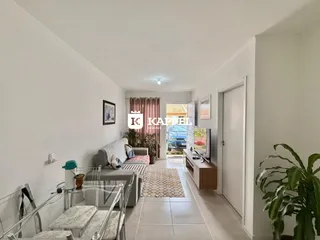 Sala de estar com sofá e mesa de vidro em um ambiente claro.