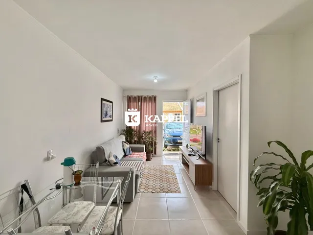 Sala de estar com sofá e mesa de vidro em um ambiente claro.