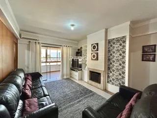 Sala de estar com sofás de couro pretos e piso de carpete.