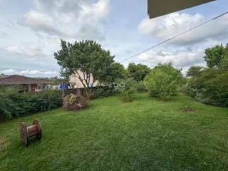 Vista de um jardim gramado com árvores ao fundo.