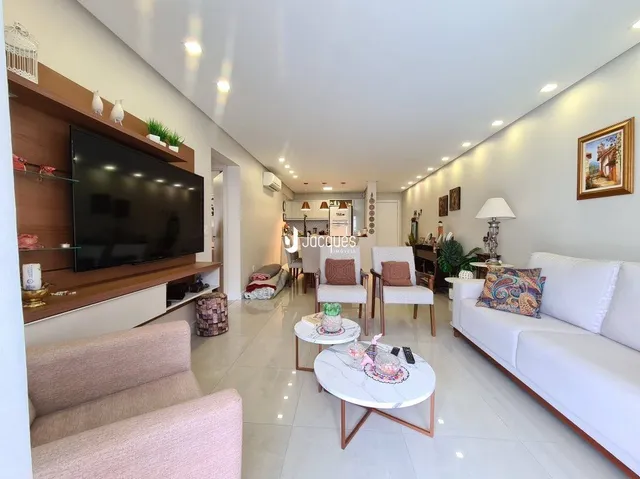 Sala de estar moderna com sofá branco e televisão.