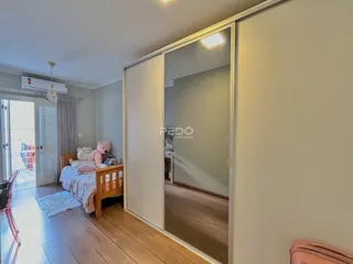 Quarto com piso de madeira e porta de vidro.