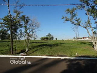 Vista externa de um terreno gramado com árvores.