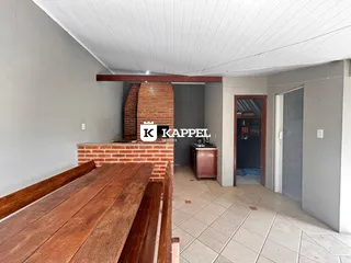 Uma sala de jantar com mesa de madeira e lareira de tijolos exposta.
