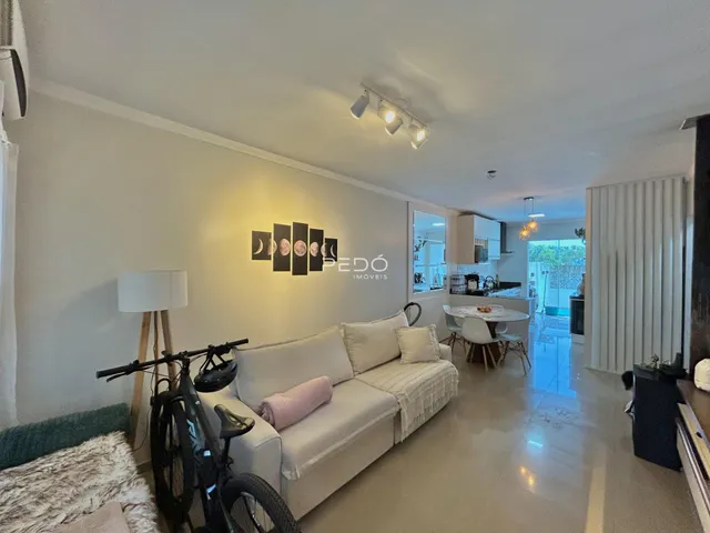 Sala de estar com sofá branco e piso de madeira.