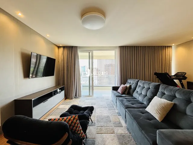 Sala de estar com sofá cinza e televisão em um apartamento no Brasil.