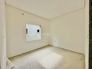 Imagem de um cômodo vazio com paredes brancas e piso de concreto.