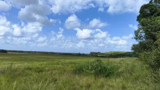 Paisagem de campo aberto com vegetação verde sob um céu azul nublado.