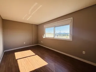 Foto de uma sala de estar com piso de madeira e janela.