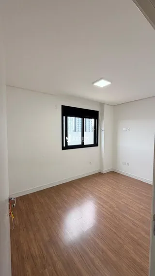 Foto do interior de uma sala com piso de madeira e janela.