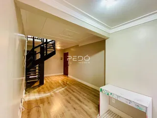 Hall de entrada com escada e piso de madeira em imóvel no Brasil.