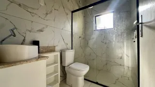 Banheiro com revestimento em mármore e box de vidro transparente.