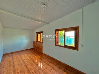 Interior de uma sala com piso de madeira e janelas de madeira.