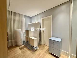 Quarto com cama e móveis brancos em um ambiente claro.
