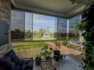 Sala com grandes janelas oferecendo uma vista para a paisagem rural.