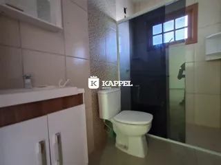 Foto de um banheiro com revestimento de azulejos brancos e um vaso sanitário.
