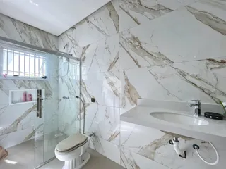 Foto de um banheiro com revestimento de mármore e box de vidro.