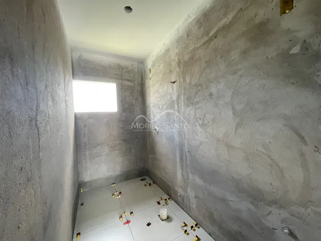 Interior de um cômodo com paredes de concreto aparente e piso claro.