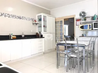 Interior de uma cozinha e sala de jantar com armários brancos.