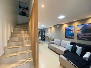 Vista de um hall com escadaria e sala de estar moderna.