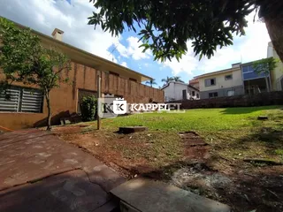 A fachada da residência mostra um muro e uma área gramada.
