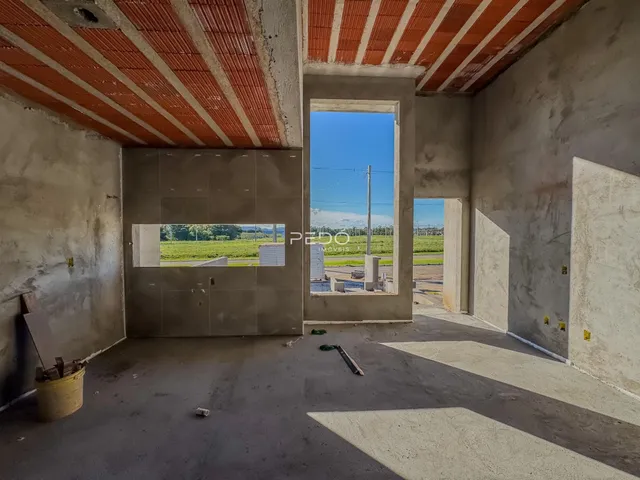 Interior de uma área em construção com paredes de concreto aparente e teto de telhas.
