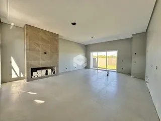 Ambiente interno amplo com piso claro e parede de destaque em pedra na residência.
