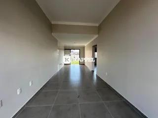 Corredor interno de um imóvel com piso de cerâmica e paredes claras.