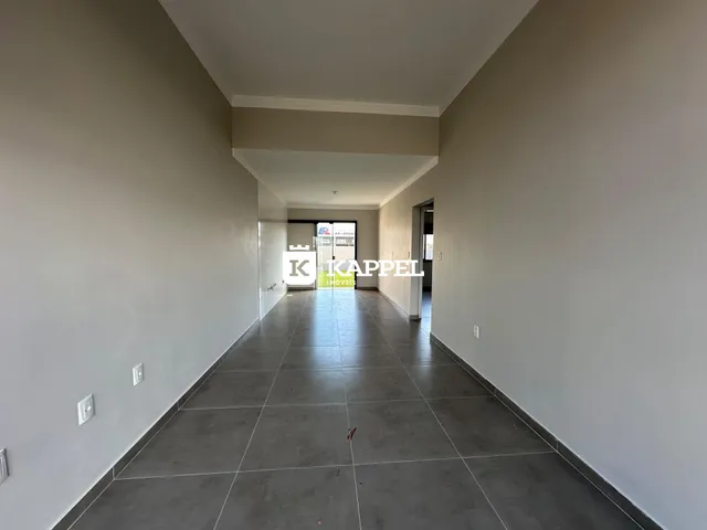 Corredor interno de um imóvel com piso de cerâmica e paredes claras.