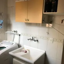 Banheiro com bancada e revestimento de azulejos brancos.