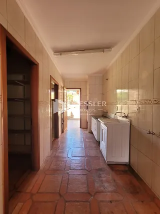 Passagem interna de um corredor com piso de tijolo.