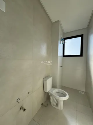 Um banheiro com paredes brancas e piso de cerâmica.
