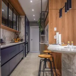 Foto de uma área de cozinha com revestimento de madeira e bancada clara.