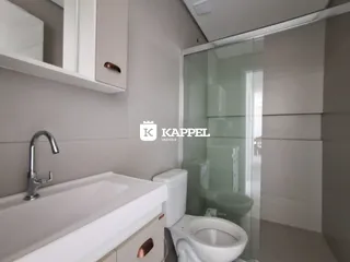 Banheiro moderno com bancada branca e box de vidro transparente.