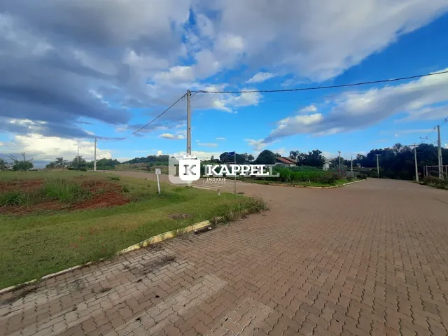 Vista externa da entrada de uma propriedade em Lajeado, Brasil, mostrando uma estrada pavimentada e área gramada.