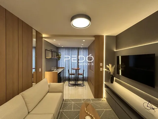 Sala de estar com revestimento de madeira e sofá claro.
