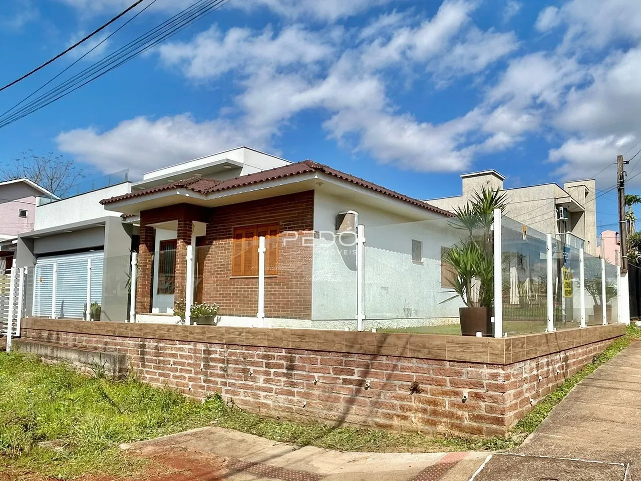 Fachada de uma casa em Lajeado, Brasil, com muro de tijolos e cerca de vidro.