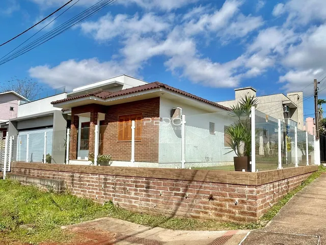 Fachada de uma casa em Lajeado, Brasil, com muro de tijolos e cerca de vidro.
