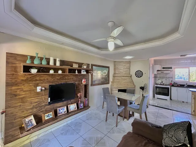 Sala de estar com painel de madeira e televisão em um imóvel no Brasil.