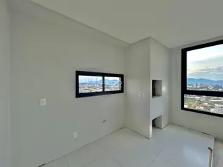 A sala apresenta paredes brancas e um piso de cerâmica com vista para a paisagem.