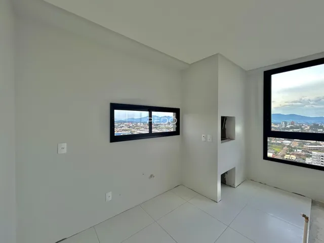 A sala apresenta paredes brancas e um piso de cerâmica com vista para a paisagem.