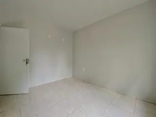 Um corredor interno com paredes brancas e piso de cerâmica claro.