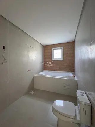 Banheiro moderno com banheira e revestimento de parede em Lajeado.